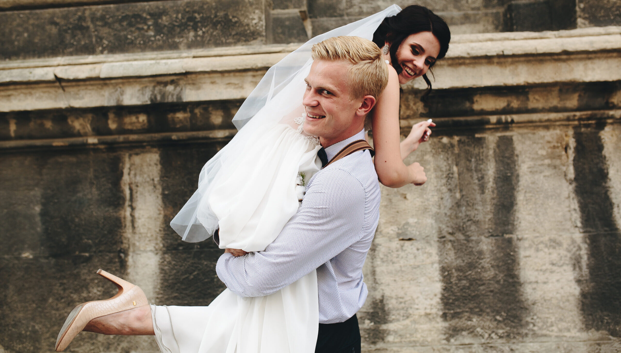 groom carries his bride in his arms through the old town