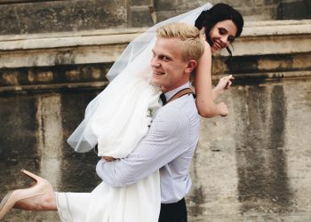 groom carries his bride in his arms through the old town